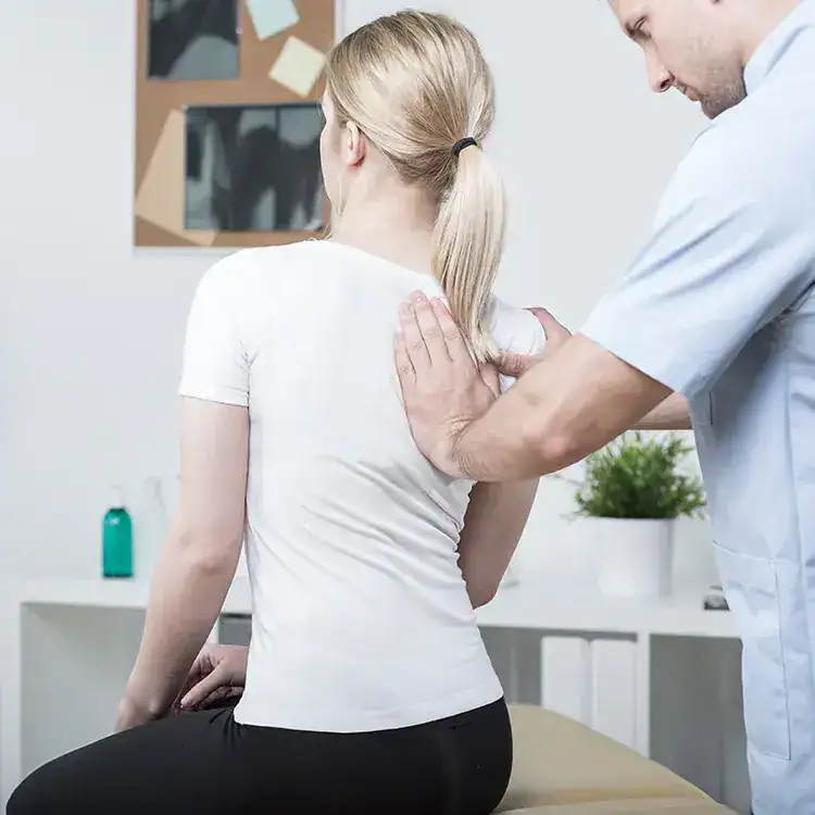 Osteopath examining woman's shoulder for treatment or assessment.