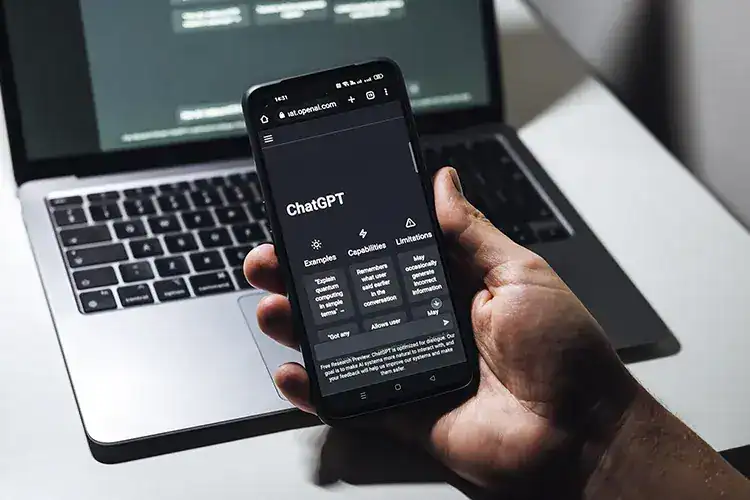 ChatGPT on smartphone with laptop.