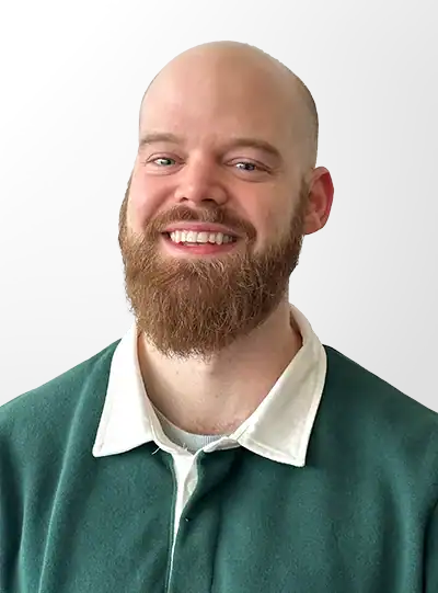 Smiling man with beard in green sweater.